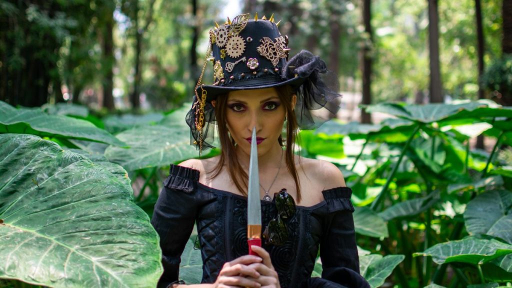 Steampunk woman in a garden holding a knife against her lips