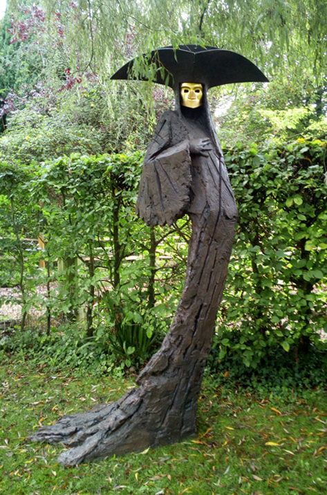 Eerie statue of a gold-faced figure in a wide-brimmed costume