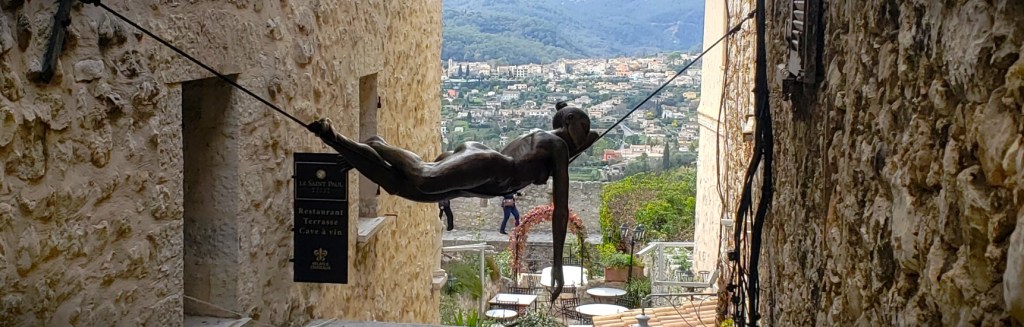 Statue of a woman lying on a wire between buildings